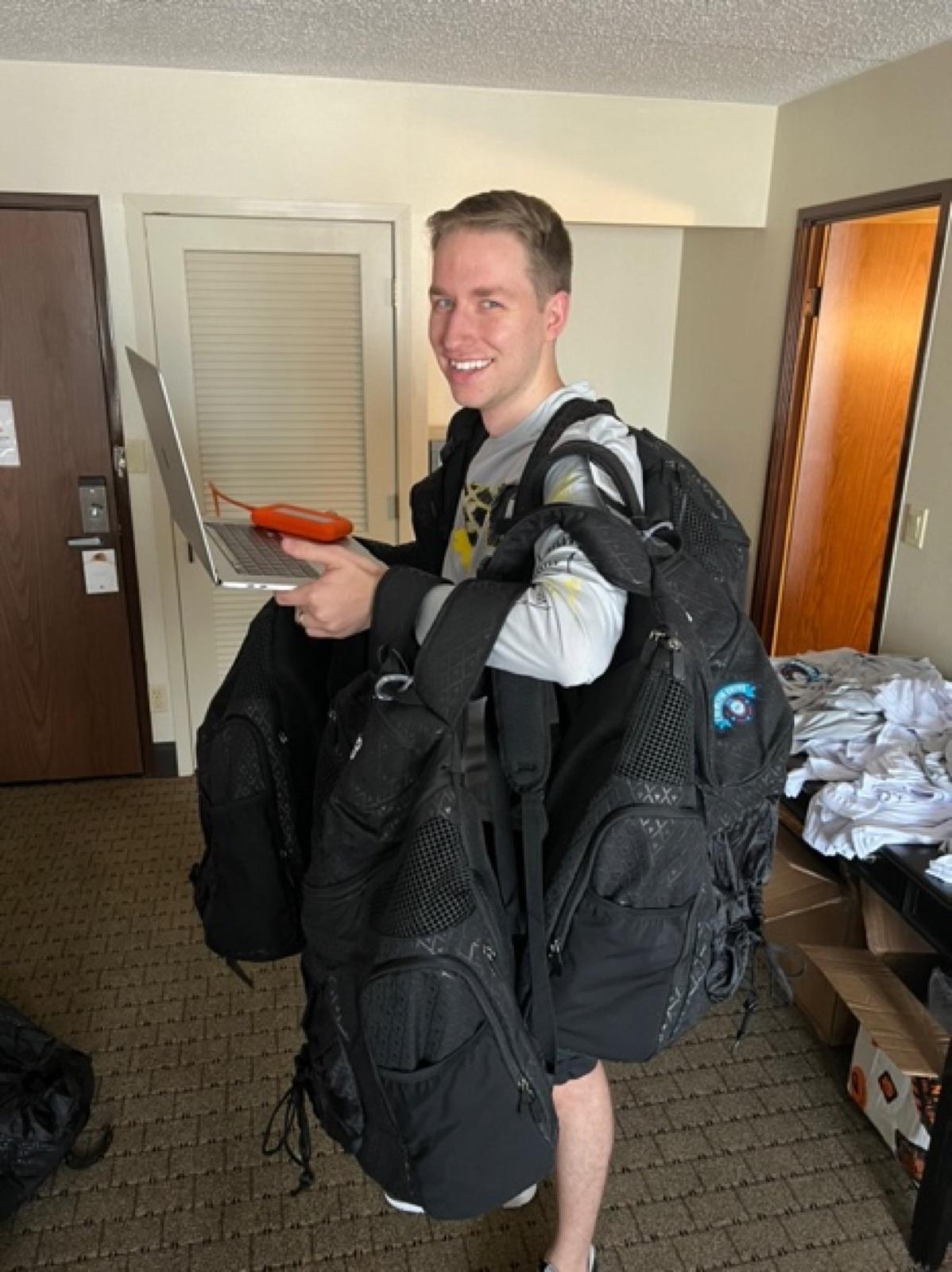 A young Zach carrying backpacks and a laptop