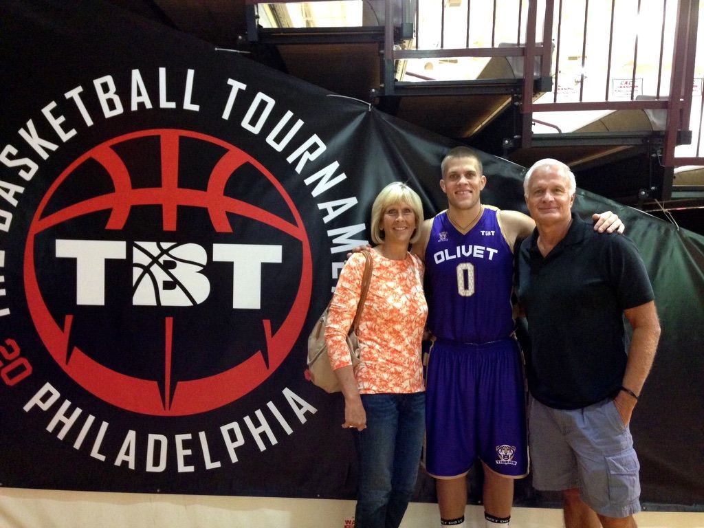 Matt in his Olivet jersey with his mom and dad in front of the TBT Philadelphia banner at his first tournament in 2014